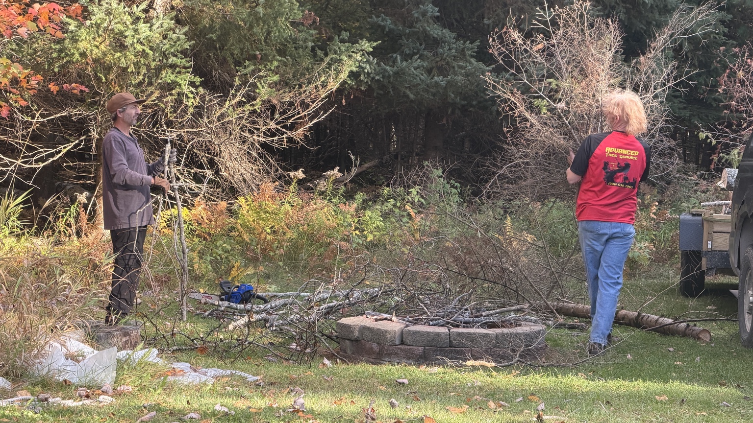 Two crew members gathering branches and brush on a job site